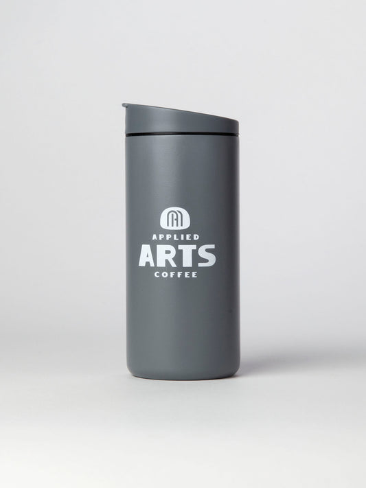 Miir 12oz Flip Traveler in Basal (grey inspred by the marine mist of the pacific northwest) with Applied Arts Coffee logo in White, photographed on a white background.